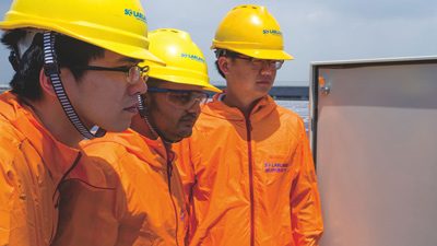 Engineers reviewing an electrical control cabinet at a solar installation