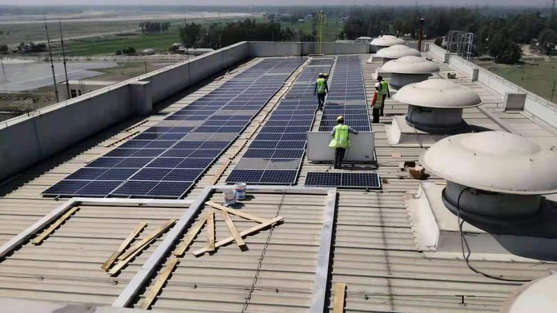 Site team in full PPE installing solar modules on an industrial rooftop